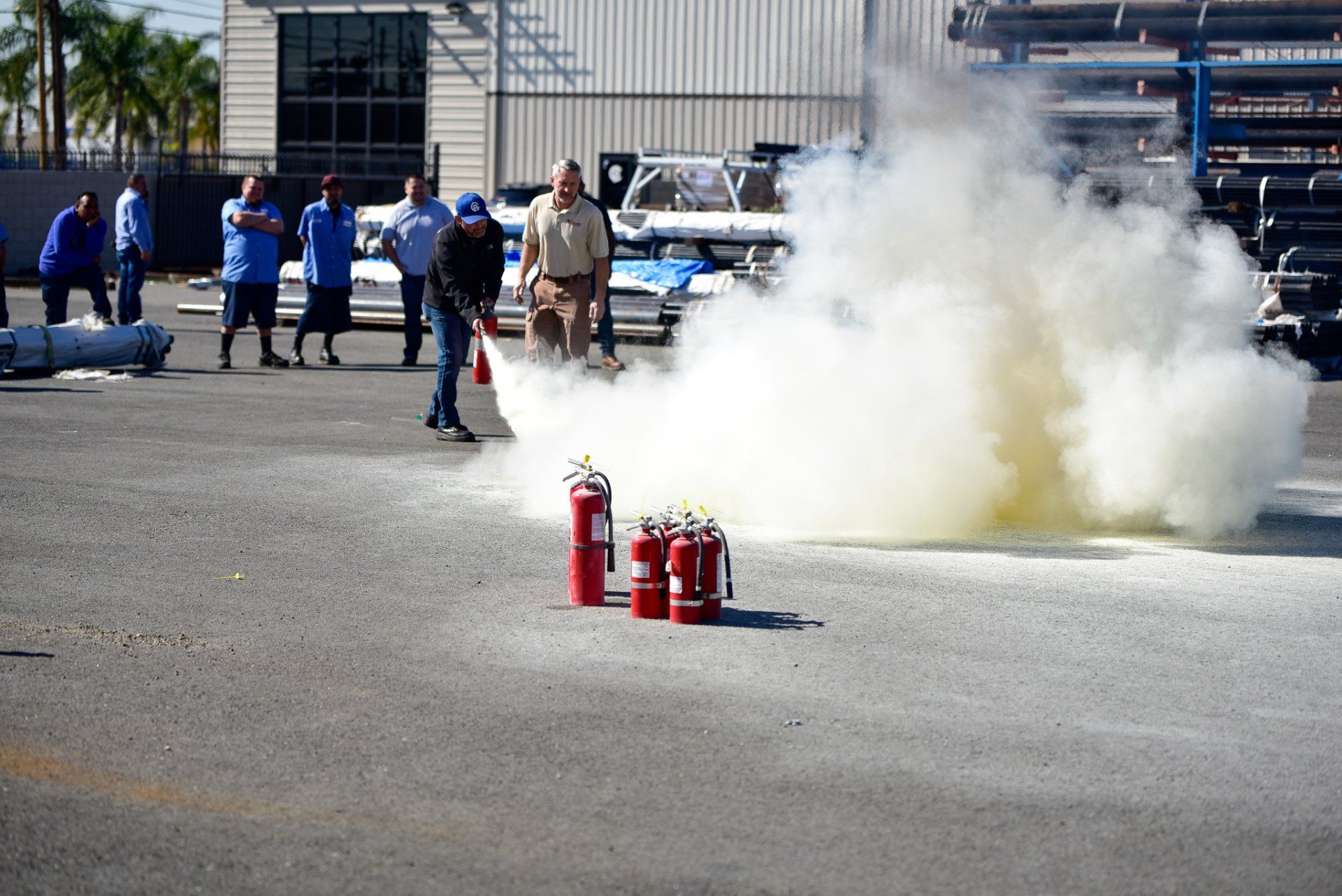 Fire extinguisher training with thick white smoke and safety personnel on a paved lot