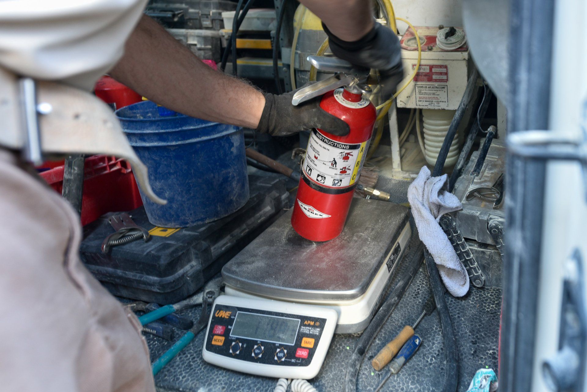 Technician using a fire extinguisher in a cluttered vehicle or workshop interior