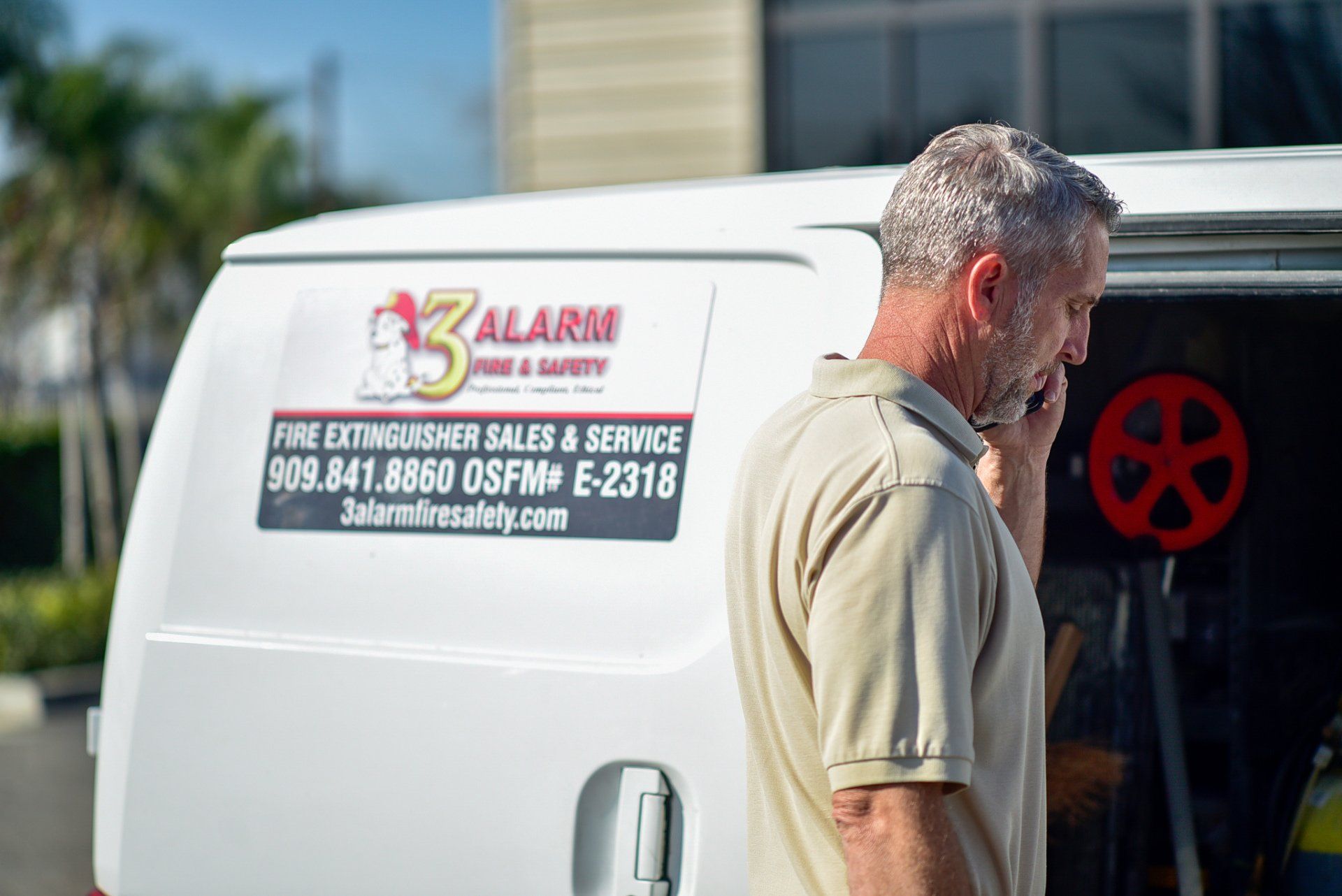 Man standing beside a white service van with A Alarm branding and phone numbers on the side