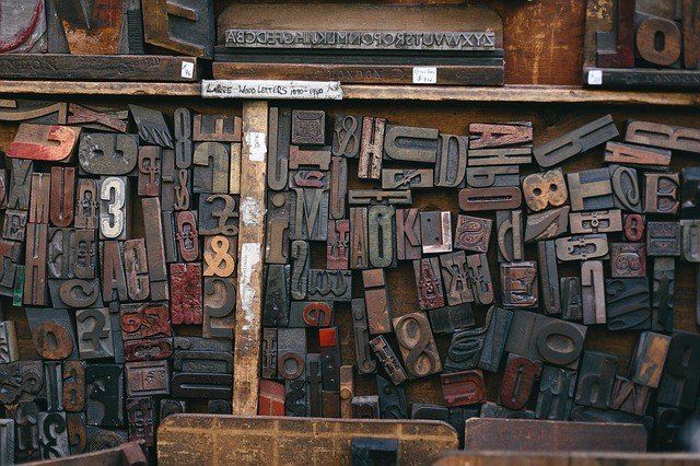 A collection of various vintage wooden letterpress blocks stored on shelves in a workshop.