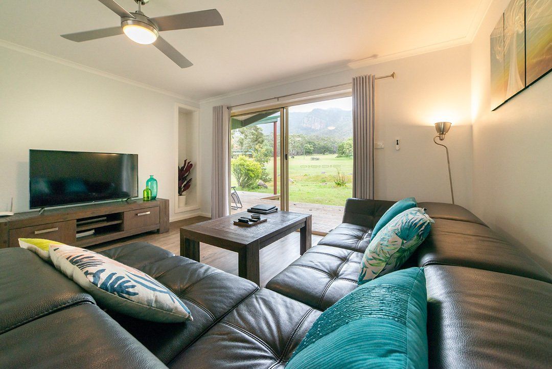 Spacious living area opening to large deck with BBQ and mountain views at Hideaway Villa, Halls Gap Valley Lodges.