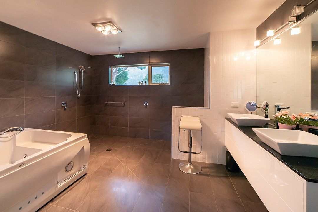Main En-suite bathroom, featuring huge spa, walk-in shower, and make-up mirror. Hideaway Villa, Halls Gap Valley Lodges.