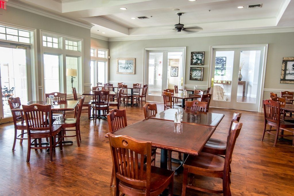 A large dining room with tables and chairs and a ceiling fan.
