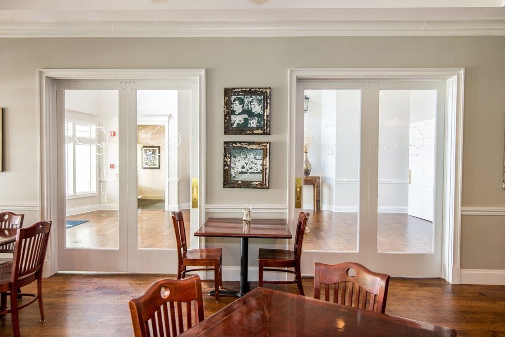 A dining room with tables and chairs and a lot of windows.