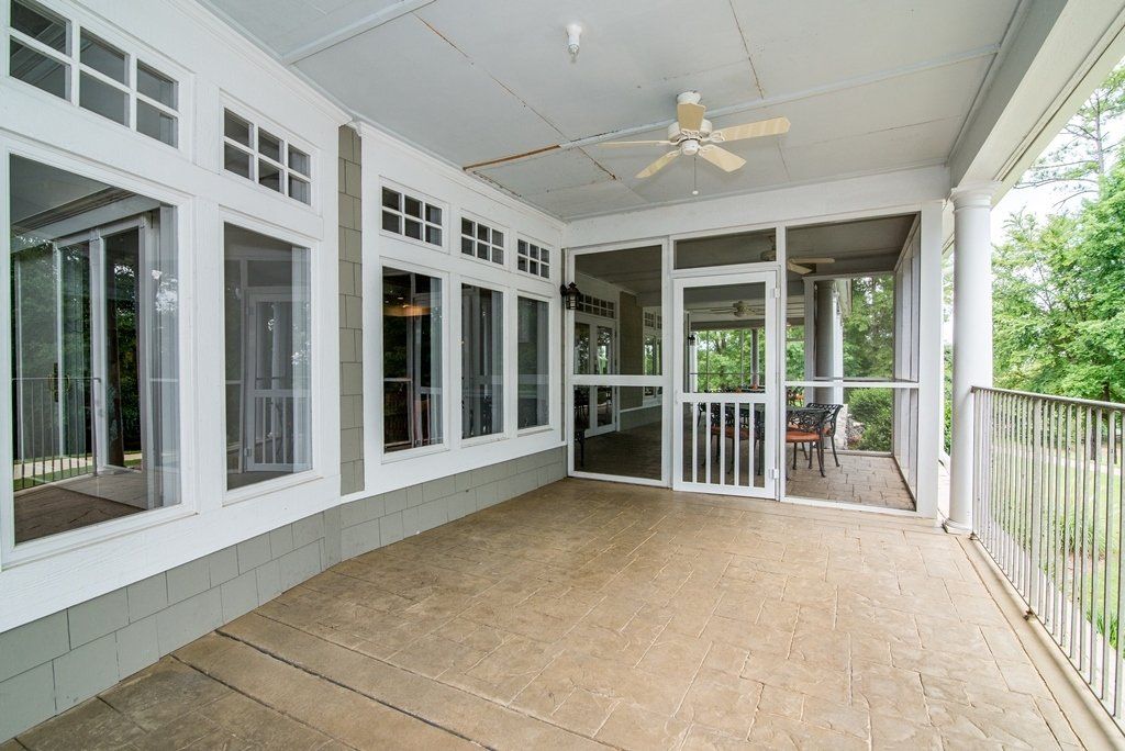 A screened in porch with a ceiling fan and lots of windows.