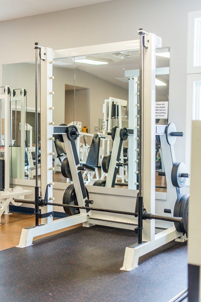 A gym with a smith machine in the middle of the room.