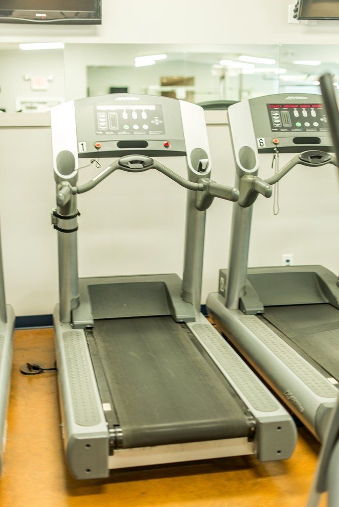 Two treadmills are lined up in a gym.