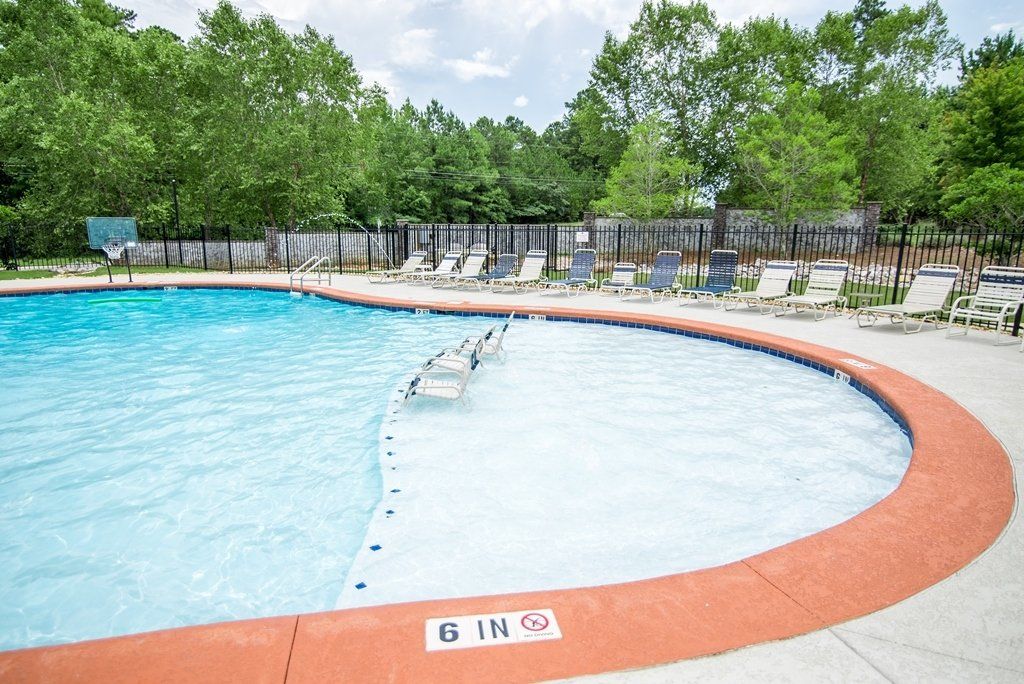A large swimming pool surrounded by chairs and trees