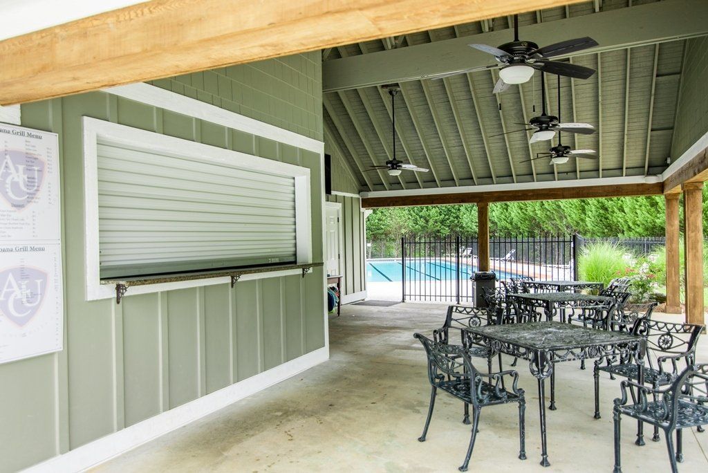 A patio area with tables and chairs and a ceiling fan.