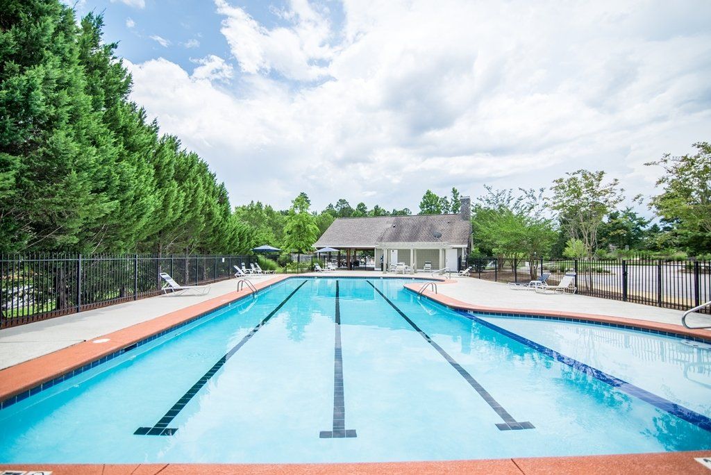 A large swimming pool surrounded by trees and a building.