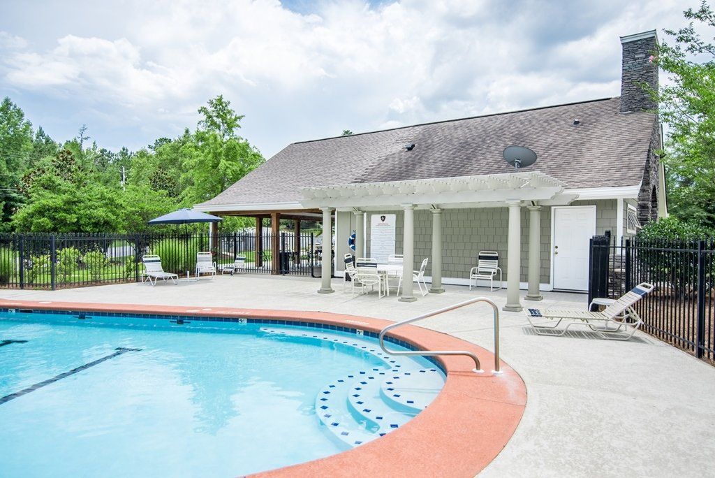 There is a large swimming pool in front of a house.
