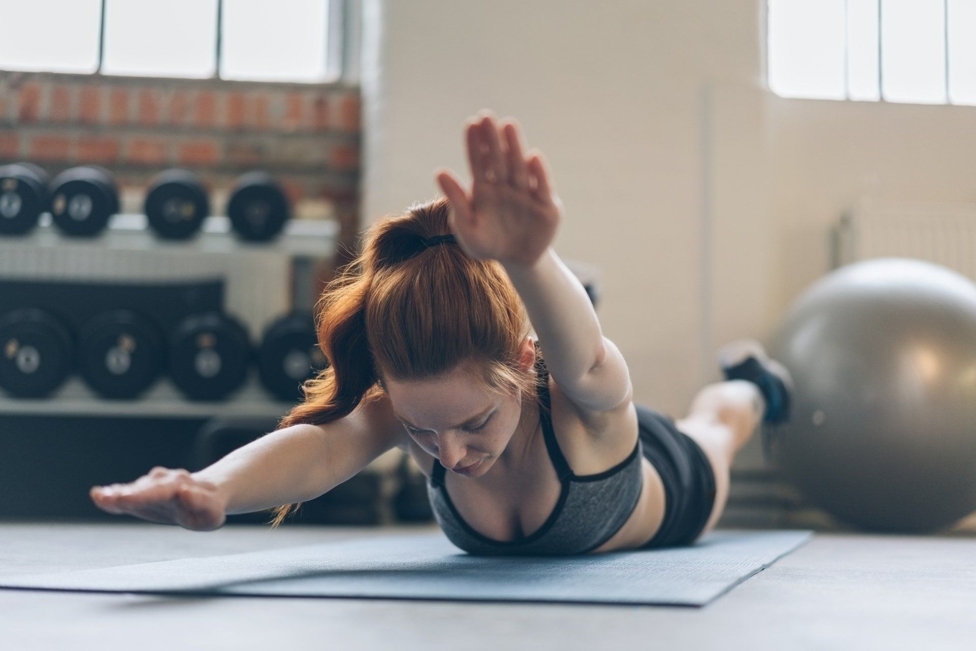 Eine Frau macht in einem Fitnessstudio Übungen auf einer Yogamatte.