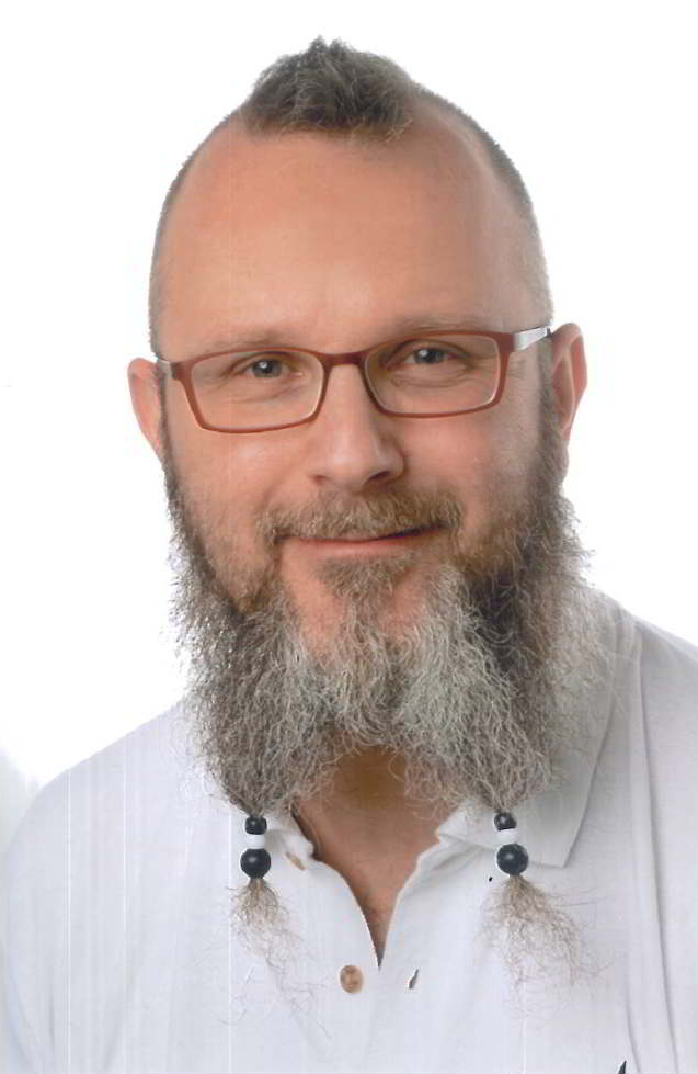 Ein Mann mit Bart und Brille trägt ein weißes Hemd.