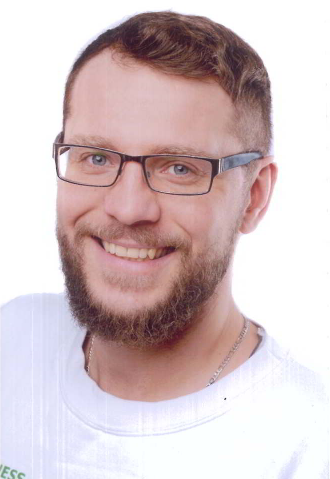 Ein Mann mit Brille und Bart lächelt in die Kamera