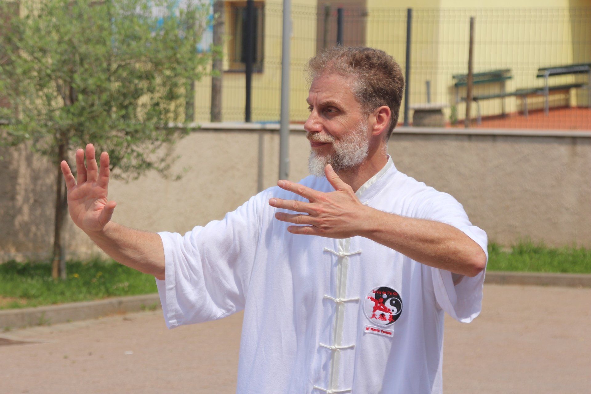 Un uomo con la barba e una camicia bianca pratica le arti marziali.