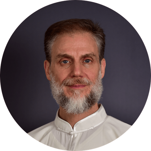Un uomo con la barba indossa una camicia bianca