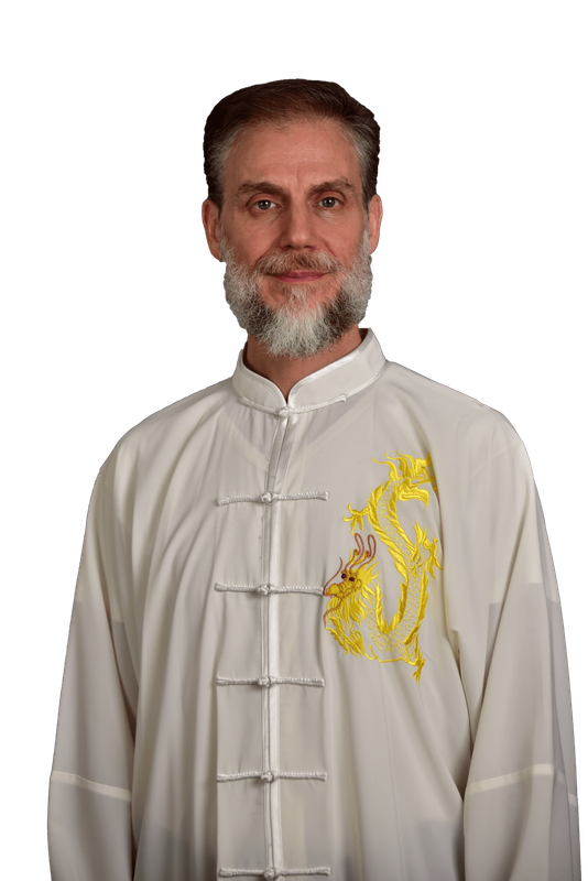 Un uomo con la barba e una camicia bianca è in piedi davanti a uno sfondo bianco.