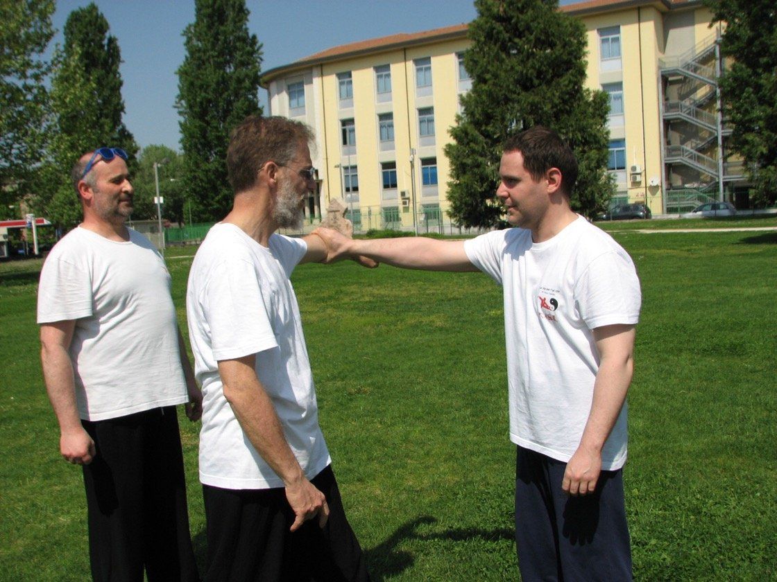 Tre uomini in camicia bianca sono in piedi in un campo erboso