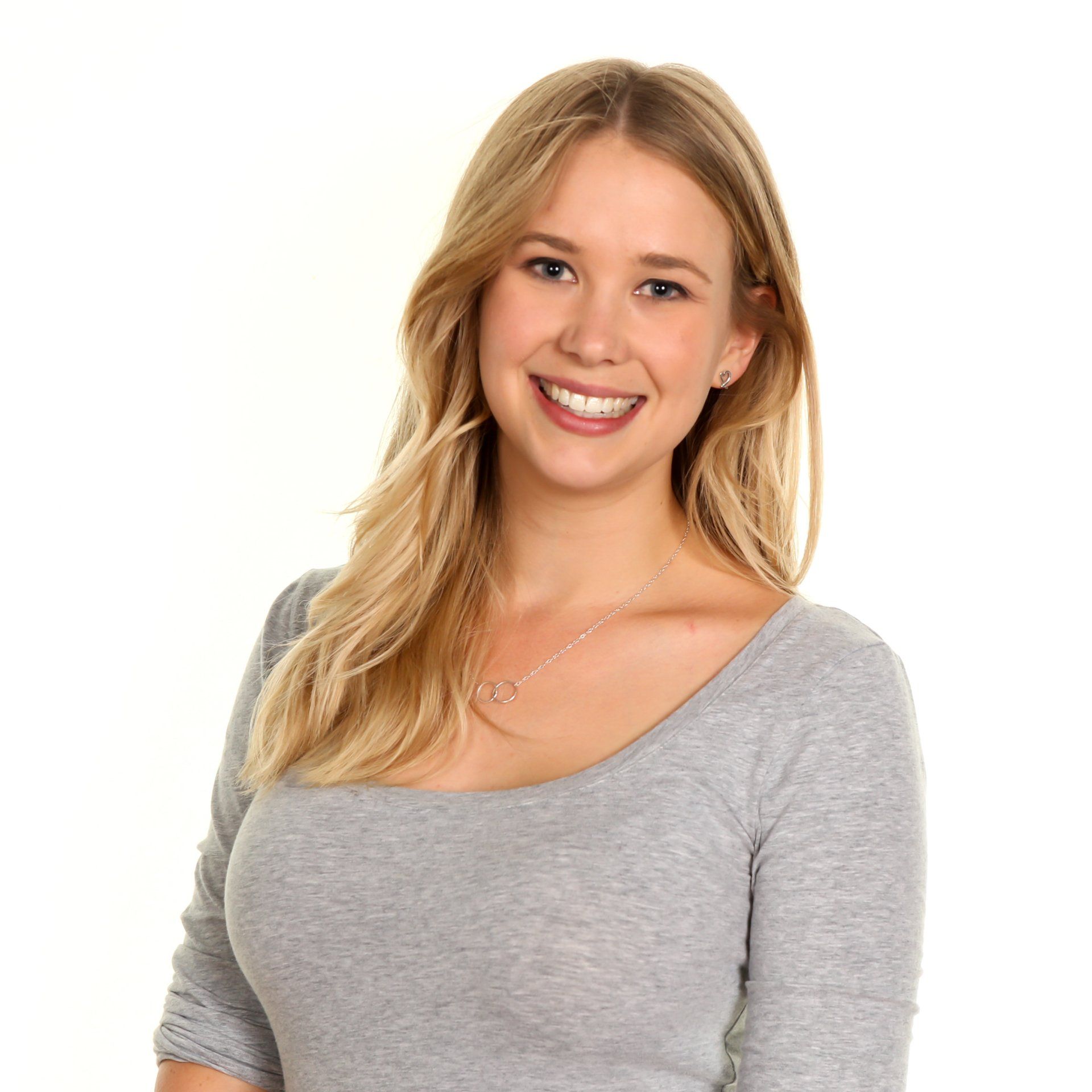 Professional headshot of young woman wearing a grey top against a white background
