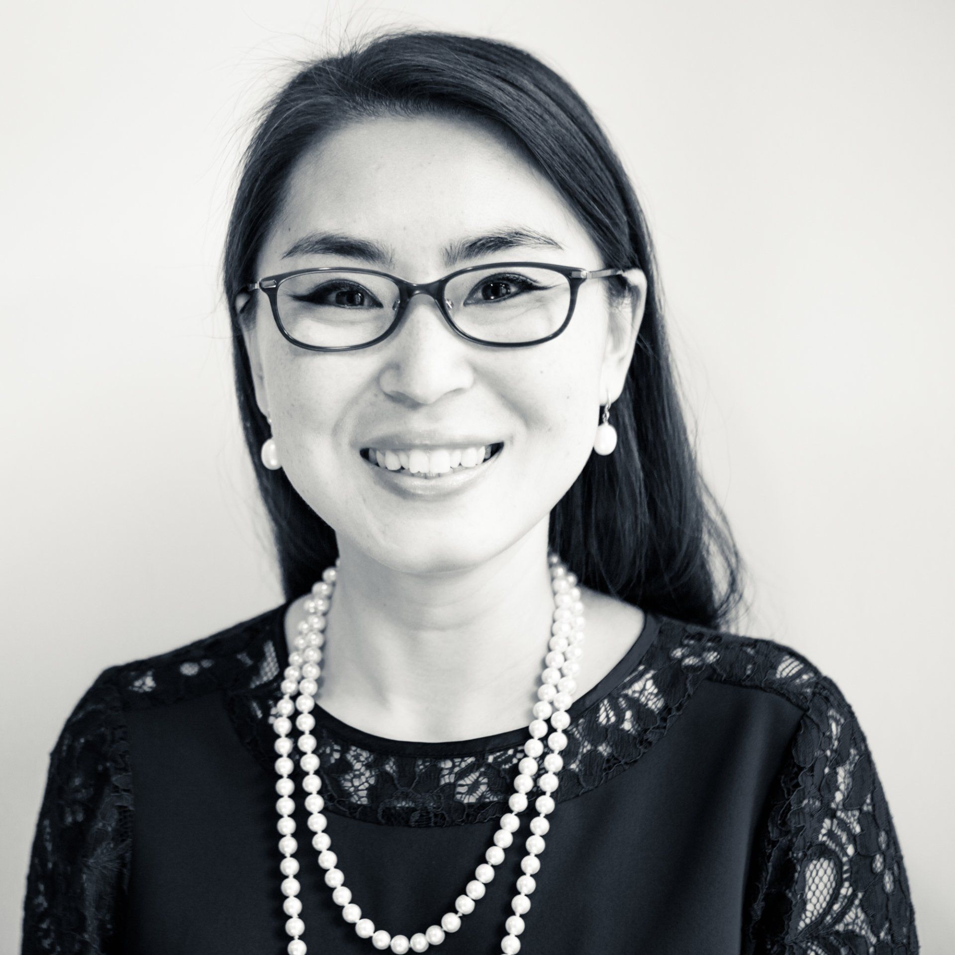 Professional headshot of an asian woman wearing glasses, a pearl necklace and earnings