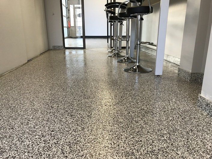 Granite-like flooring in a commercial space, with bar stools in the background and a doorway.