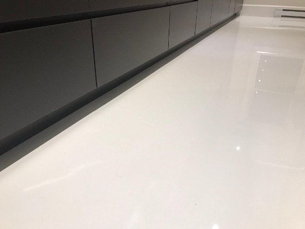 Black cabinets above a white, glossy floor in a modern kitchen.