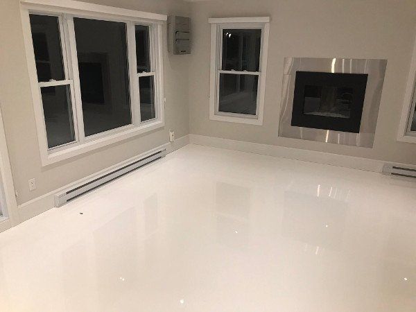 Empty room with white glossy floor, windows, and fireplace.