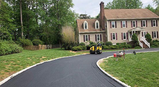 Asphalt driveway being rolled by a machine at a residential home.