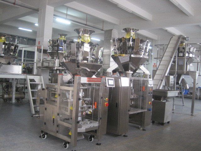 Planta industrial equipada con máquinas de procesamiento de acero inoxidable y cintas transportadoras.
