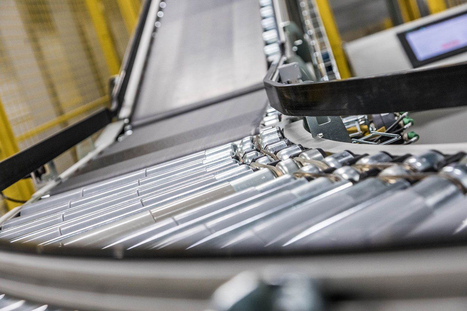 Primer plano de latas brillantes moviéndose a lo largo de una cinta transportadora en un sistema de transporte de una fábrica.