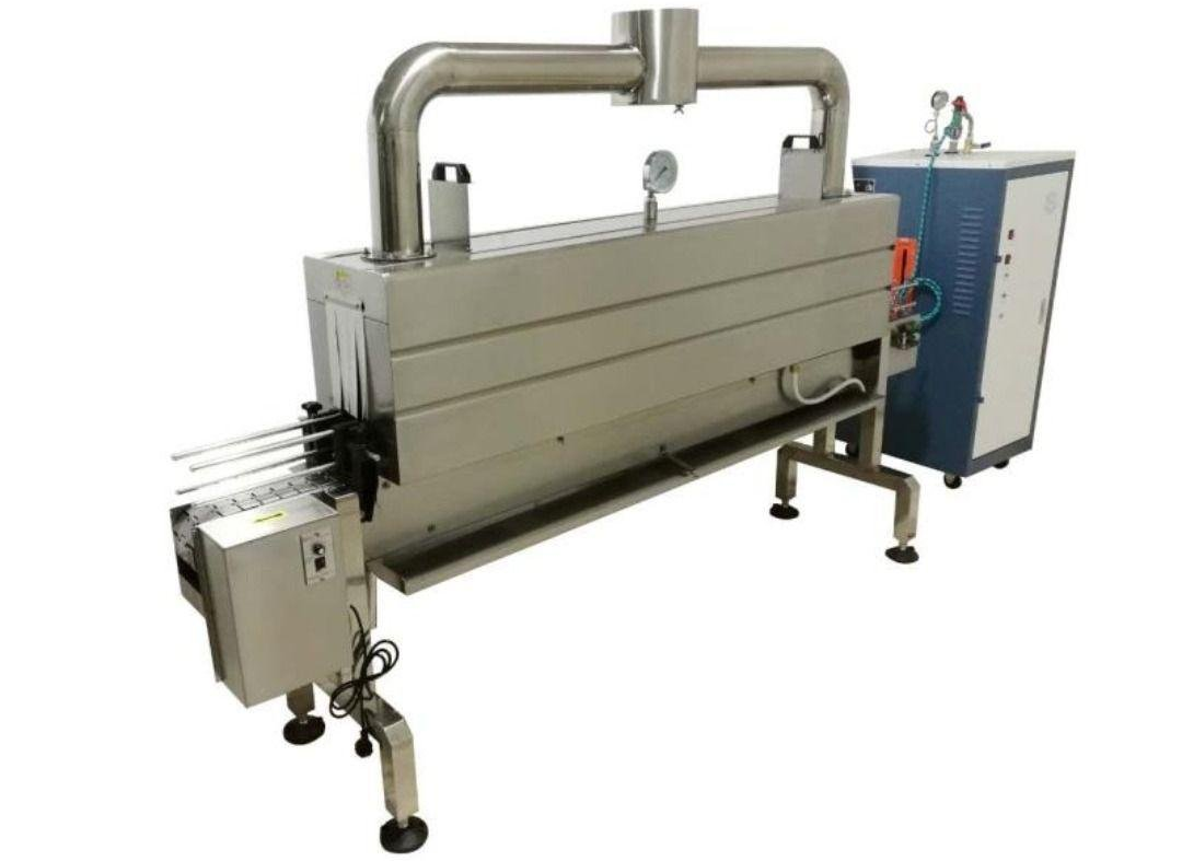 Máquina industrial con cámara metálica larga y unidad de control acoplada sobre patas.
