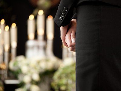 Woman stands with hands clasped in front of her in front of candles.
