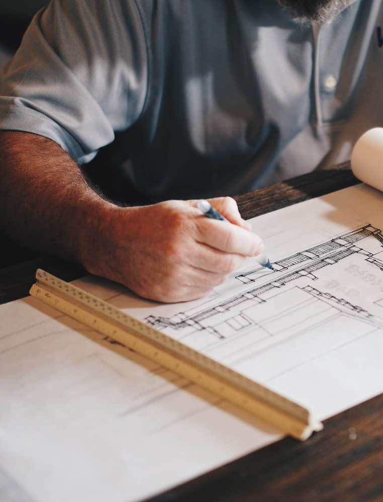 arkansas's premier restoration company mans hand holding a pencil above sketchbook with architecture designs