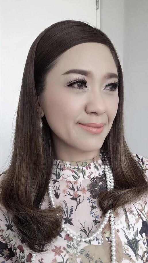 A close up of a woman wearing a floral dress and pearls.