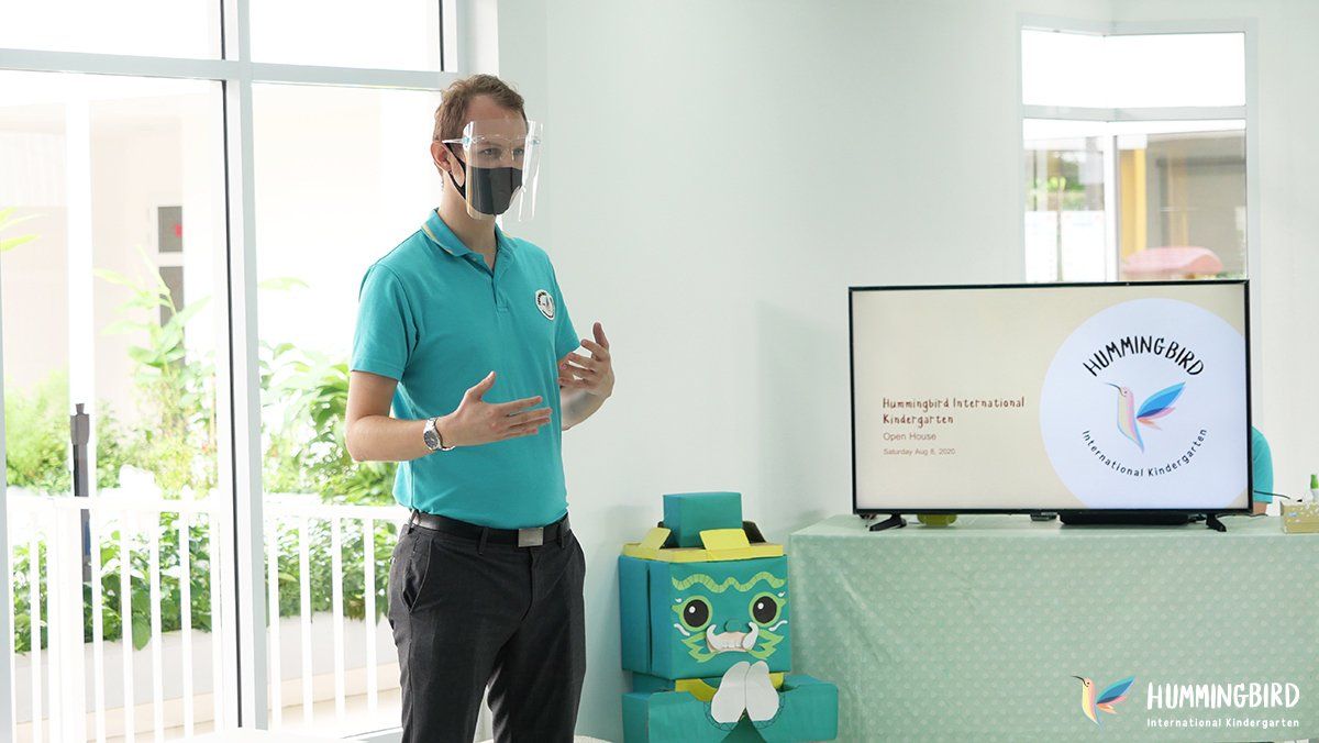 A man wearing a mask is standing in front of a television in a room.