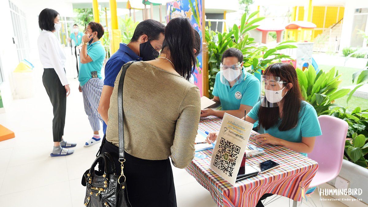 A group of people wearing face masks are standing around a table.