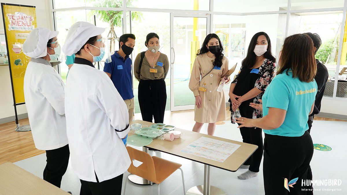 A group of people wearing masks are standing around a table.