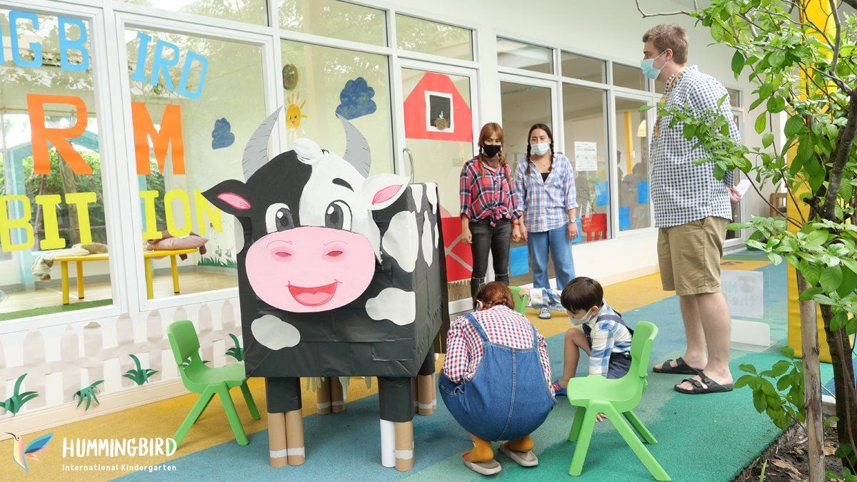 A group of people are standing around a cardboard cow.