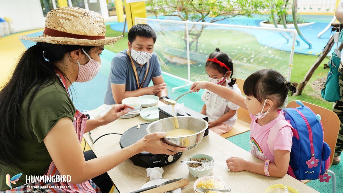 A family wearing face masks is sitting at a table eating food.