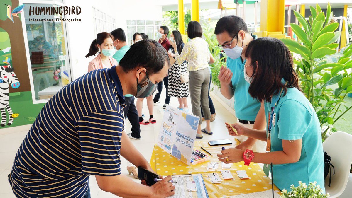A group of people wearing face masks are standing around a table.