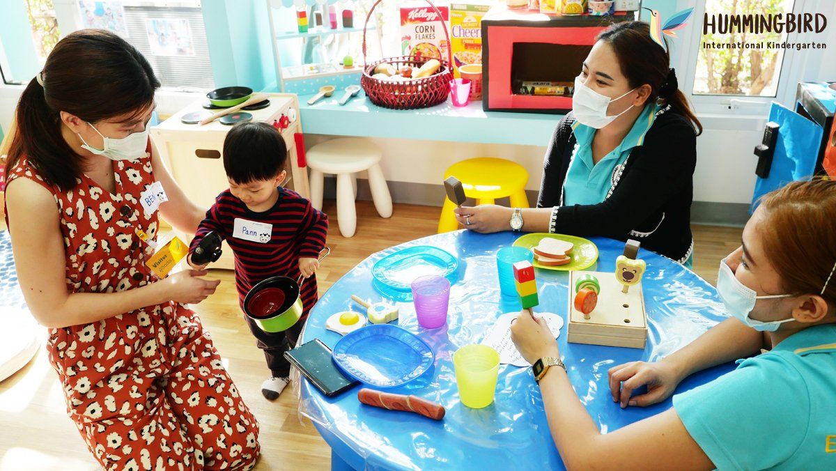A group of women and a child are sitting around a table playing with toys.