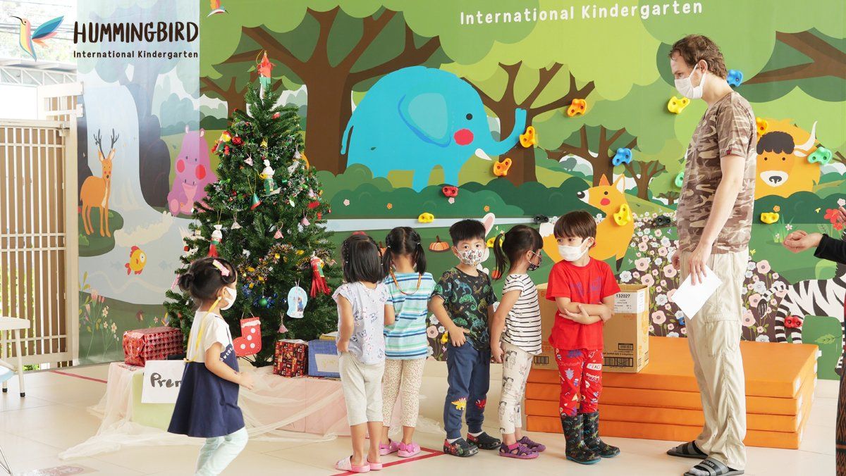 A group of children are standing in front of a christmas tree.