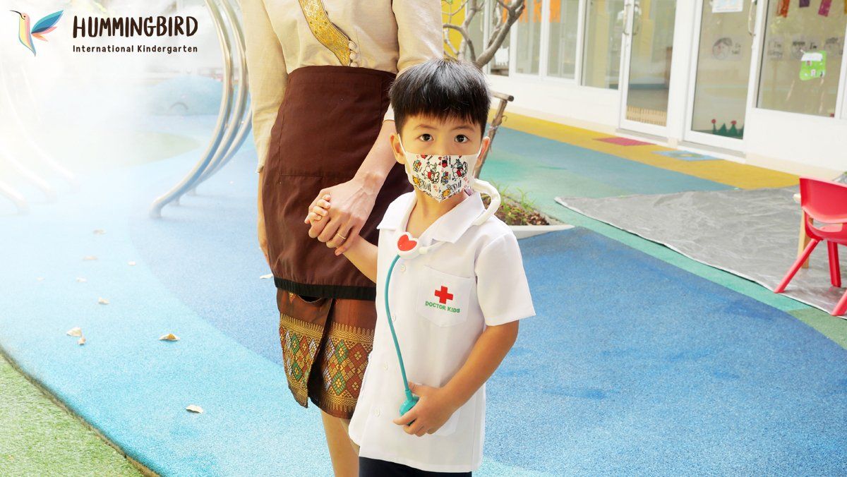 A little boy wearing a mask is holding a woman 's hand.