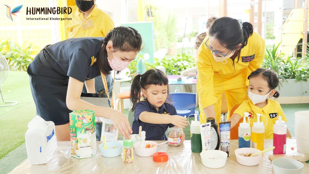 A group of children are sitting at a table making crafts.