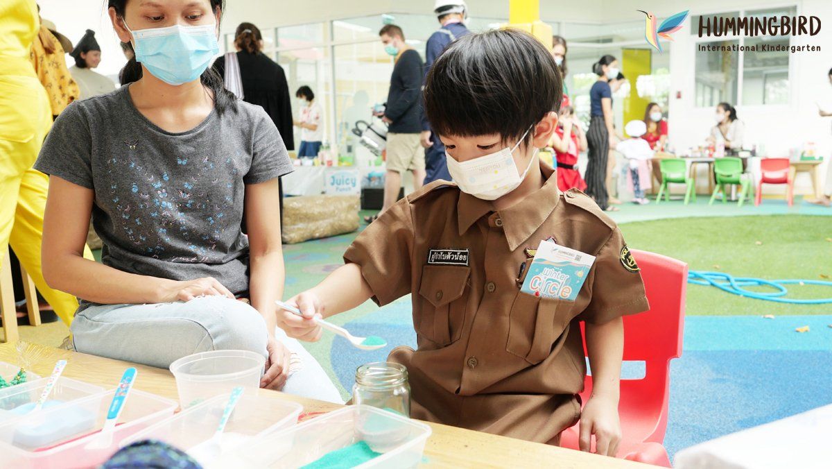A woman and a boy wearing masks are sitting at a table.