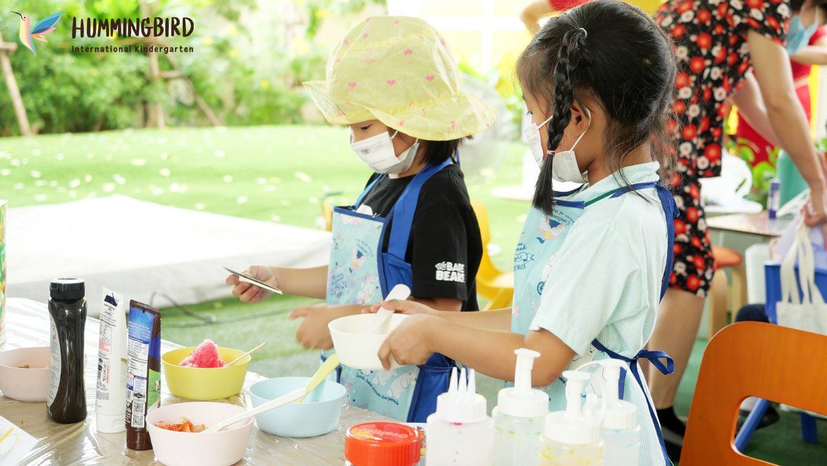 A group of children are sitting at a table making ice cream.