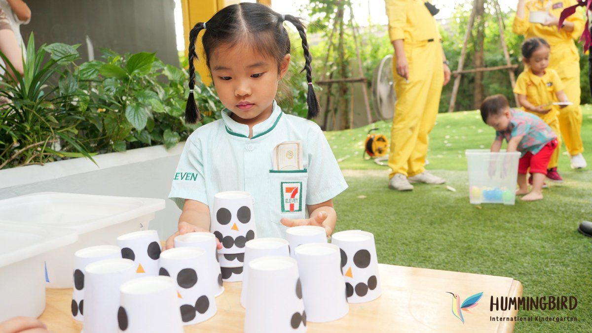 A little girl is playing with a bunch of cups on a table.