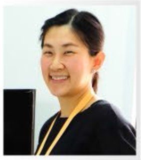 A woman wearing a black shirt and a yellow lanyard is smiling.