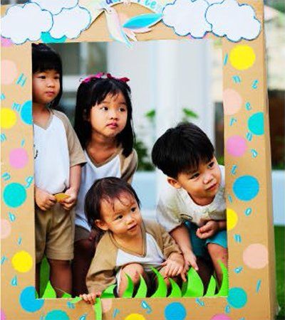 A group of children are posing for a picture in a cardboard frame.