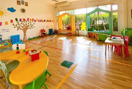 A children 's room with tables and chairs and toys on the floor.